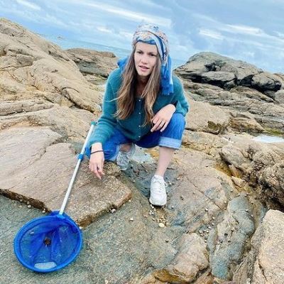 She is in a squat positing as fishing net lies to the ground next to her.